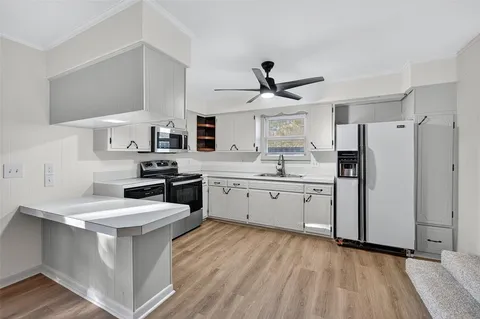 a kitchen with stainless steel appliances a sink a stove a refrigerator cabinets and a window