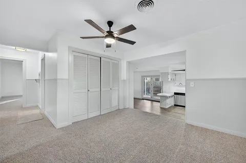an empty room with chandelier fan and windows