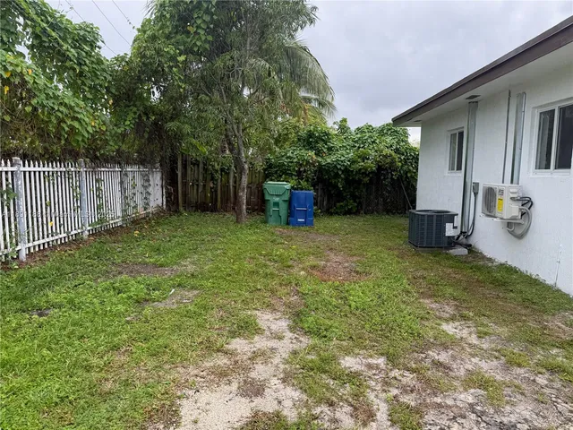 a view of a backyard with large trees and wooden fence