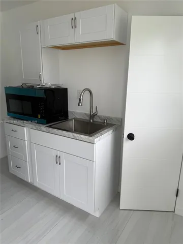 a kitchen with white cabinets and sink
