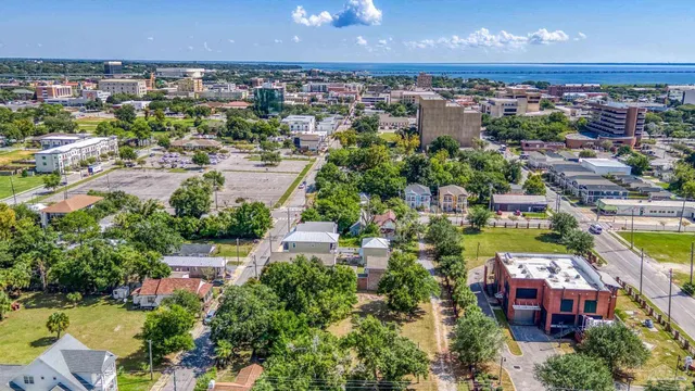 an aerial view of a city with lots of residential buildings ocean and mountain view in back