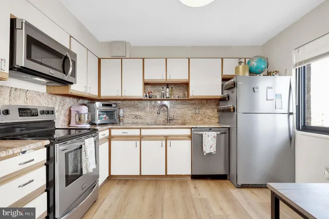 a kitchen with stainless steel appliances granite countertop a refrigerator a stove top oven a sink and dishwasher with wooden floor