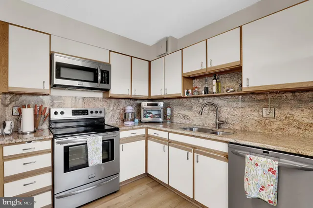 a kitchen with stainless steel appliances granite countertop grey cabinets a stove a sink and a microwave