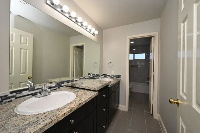 a bathroom with a granite countertop sink and a mirror