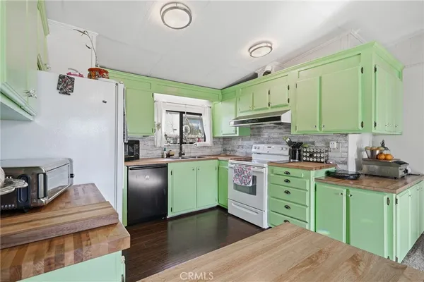 a kitchen with a refrigerator a sink dishwasher stove and a refrigerator with wooden floor