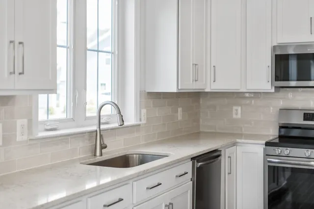 a kitchen with granite countertop white cabinets and a sink