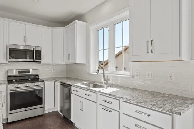 a kitchen with granite countertop white cabinets and a stove