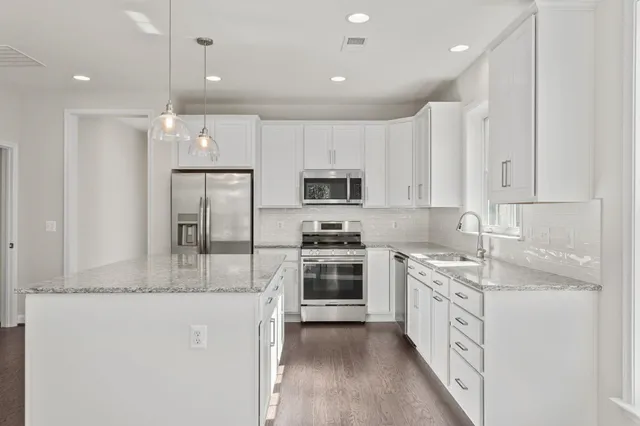 a kitchen with stainless steel appliances granite countertop a stove top oven a sink and a refrigerator