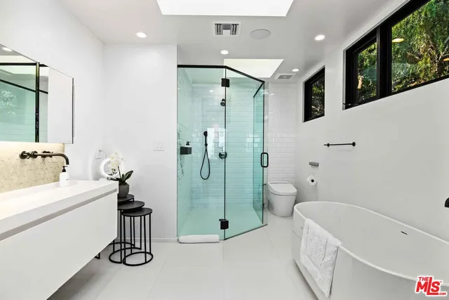 a bathroom with a double vanity sink toilet mirror and bathtub