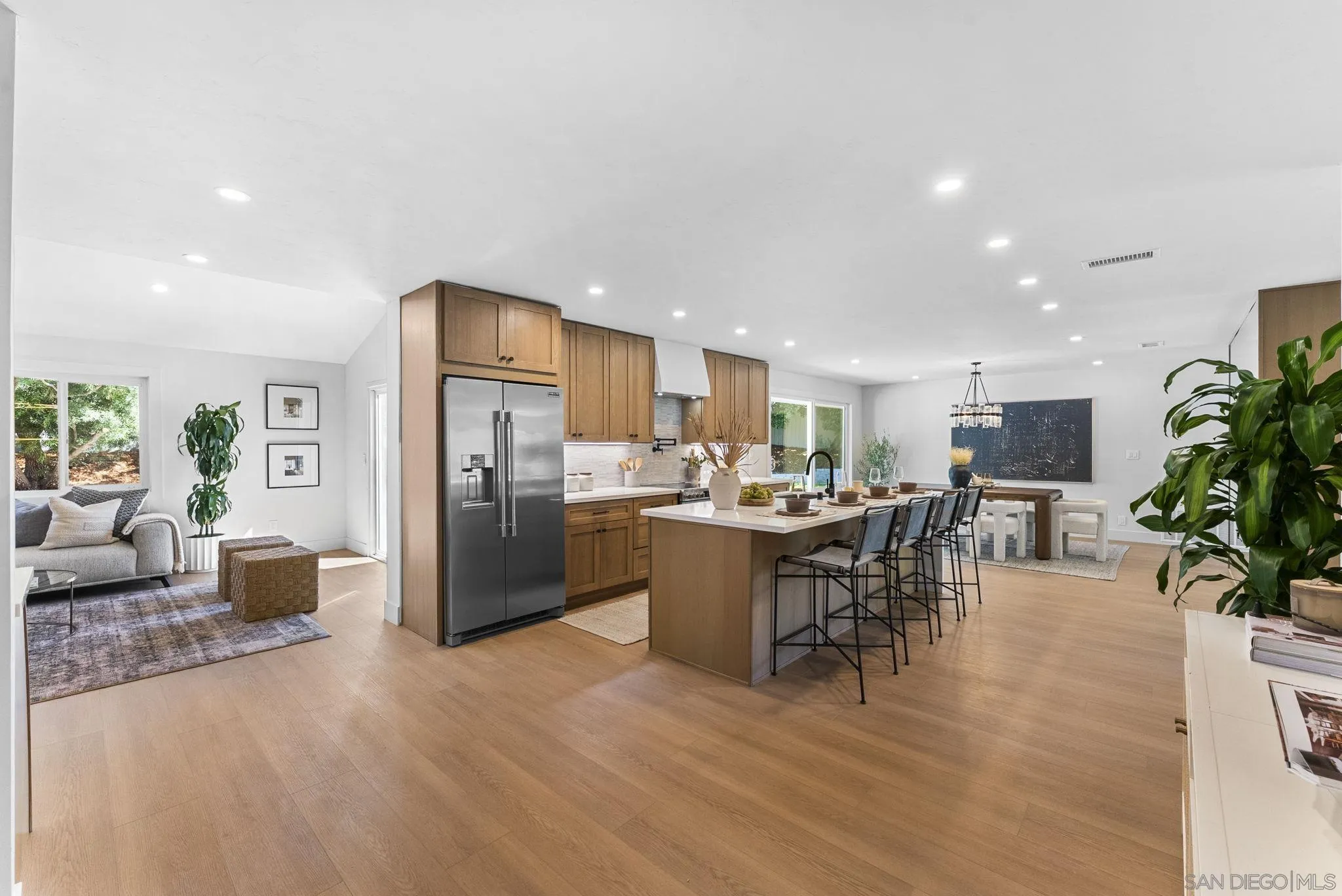 12830 Avenida La Valencia Poway, CA 92064 - Photo 8 of 47 a kitchen with stainless steel appliances kitchen island granite countertop a refrigerator a stove a sink a dining table and chairs with wooden floor