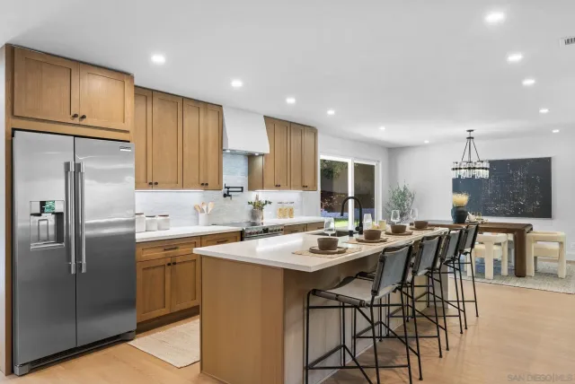 a kitchen with stainless steel appliances granite countertop a sink a stove a refrigerator cabinets and chairs