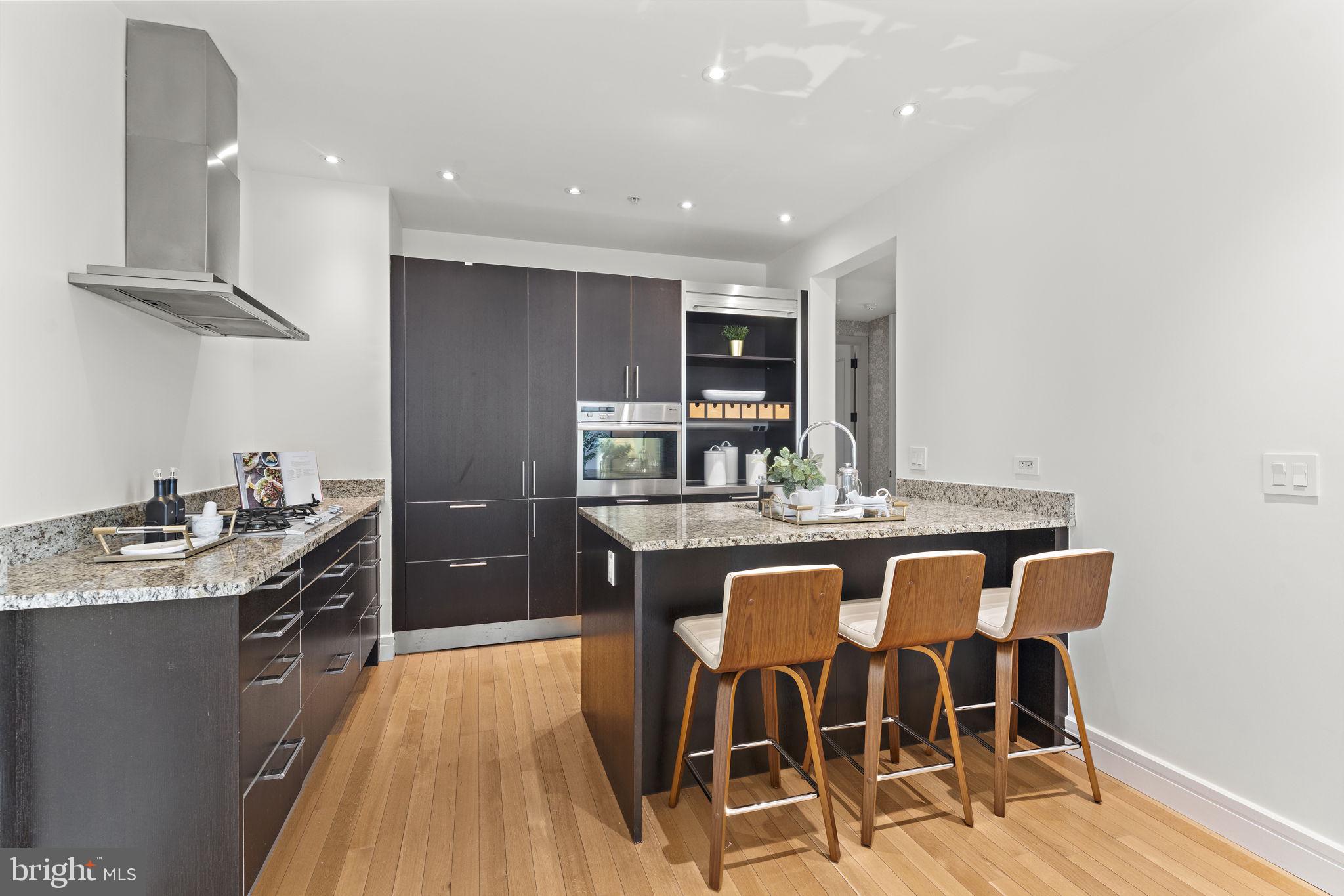 3303 Water Street Northwest, Unit 4L Washington, DC 20007 - Photo 12 of 60 a kitchen with stainless steel appliances granite countertop a stove top oven a sink a dining table and chairs with wooden floor