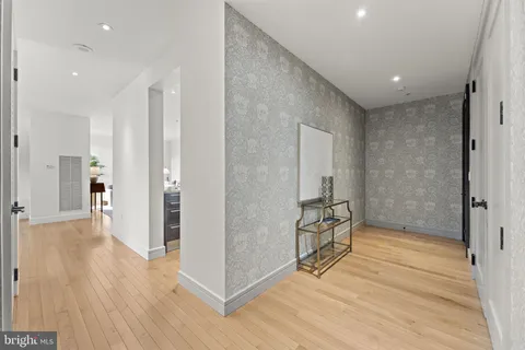a view of a hallway with wooden floor and a bathroom
