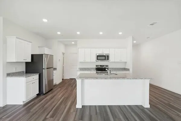 a large kitchen with stainless steel appliances kitchen island a stove a refrigerator a sink and dishwasher a oven with wooden floor