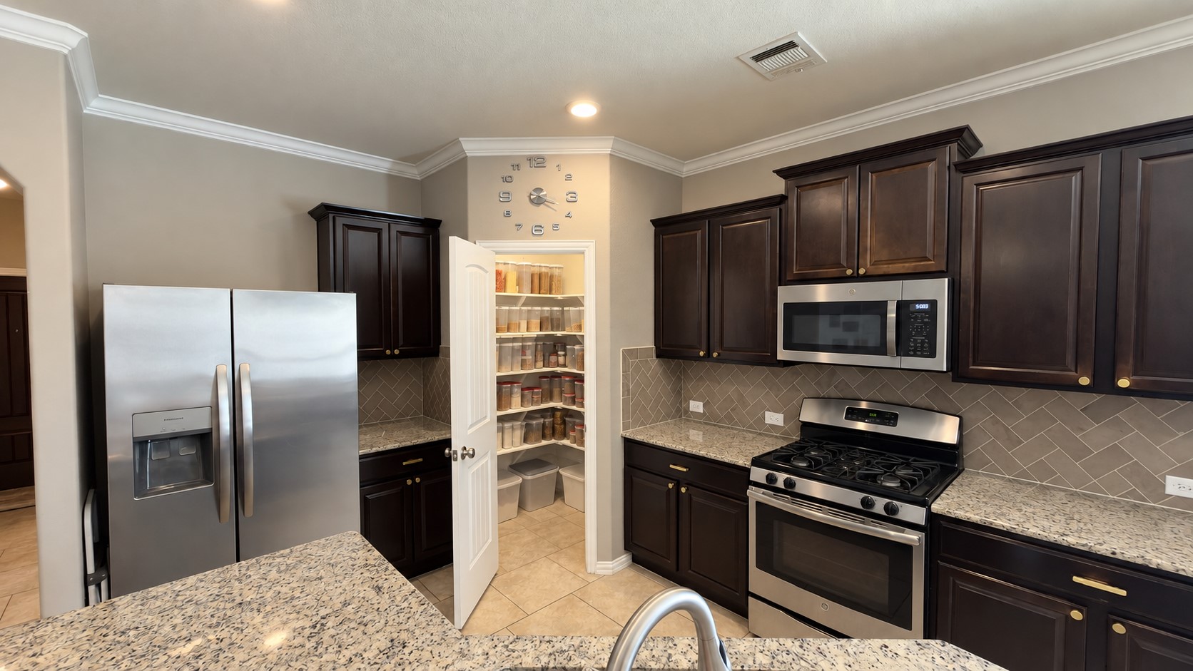 2500 Rough Berry Road Pflugerville, TX 78660 - Photo 9 of 15 Rich dark cabinetry and granite countertops frame a walk-in pantry in this modern kitchen.