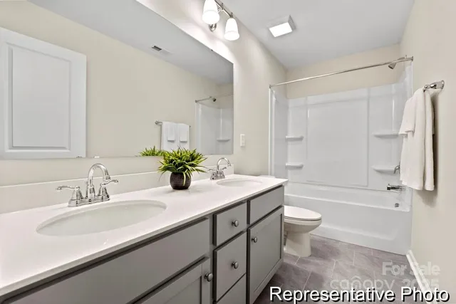 a bathroom with a sink a toilet a large mirror and shower