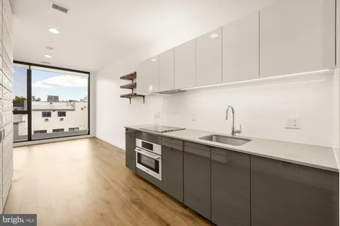 a kitchen with stainless steel appliances a sink dishwasher stove refrigerator and cabinets with wooden floor