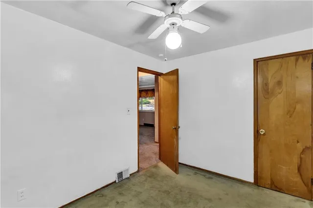 an empty room with closet and a chandelier fan