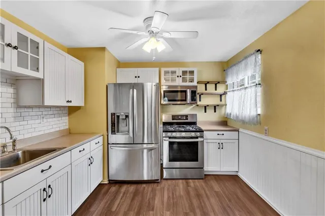 a kitchen with stainless steel appliances granite countertop a sink a stove a refrigerator cabinets and wooden floor