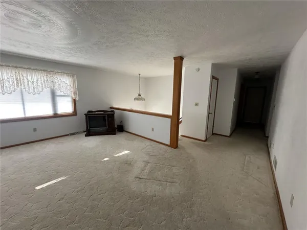an empty room with a chandelier fan and windows