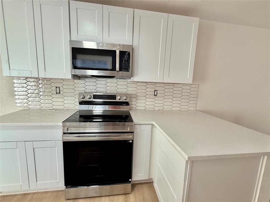 4243 Timberglen Road Dallas, TX 75287 - Photo 3 of 16 a kitchen with stainless steel appliances a stove a microwave and white cabinets