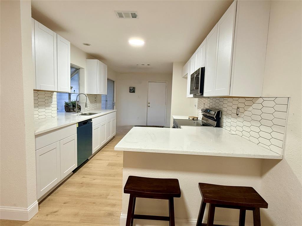 4243 Timberglen Road Dallas, TX 75287 - Photo 5 of 16 a kitchen with stainless steel appliances a sink a stove a refrigerator dining table and chairs