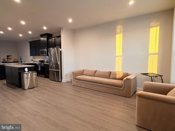 a living room with stainless steel appliances kitchen island granite countertop a couch and a refrigerator