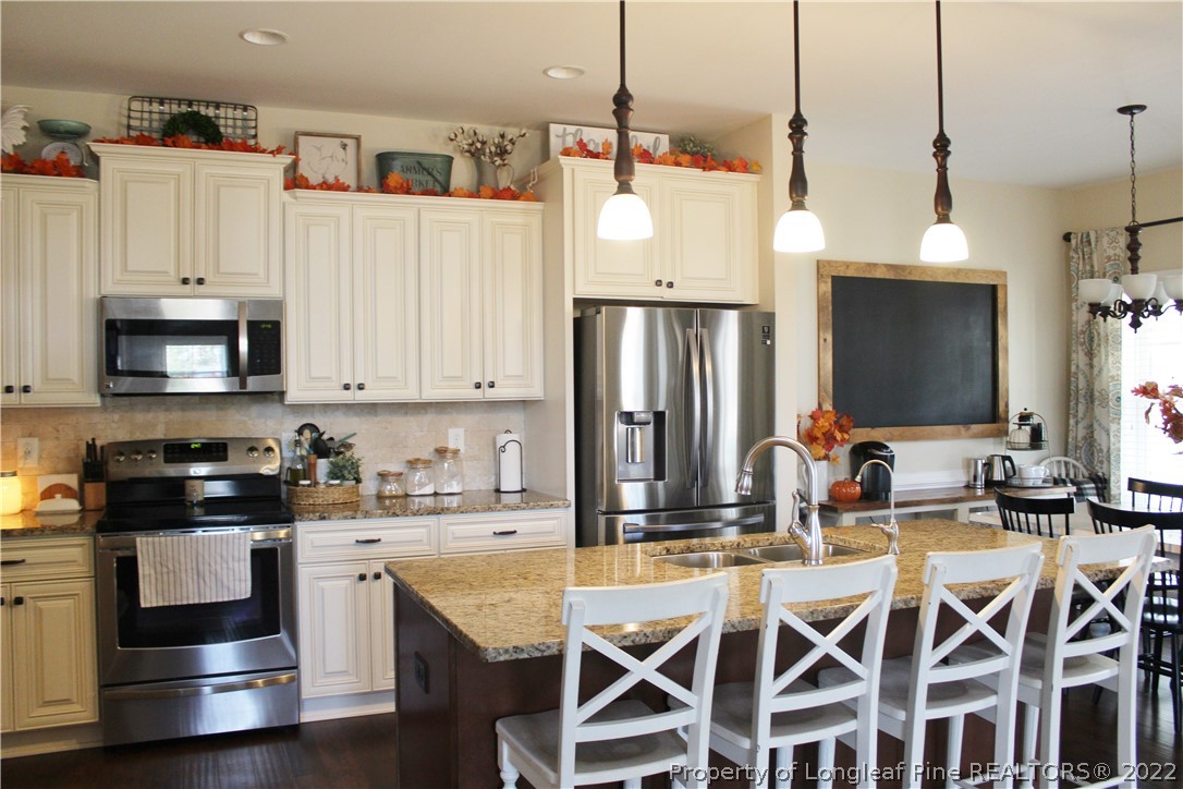 3270 Thrower Road Hope Mills, NC 28348 - Photo 8 of 50 a kitchen with stainless steel appliances kitchen island granite countertop a stove a sink and a refrigerator