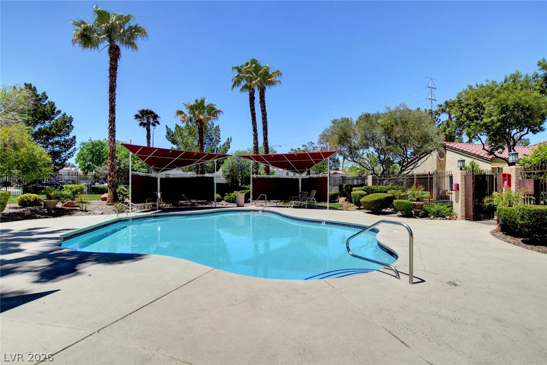 7885 West Flamingo Road, Unit 1050 Las Vegas, NV 89147 - Photo 43 of 62 A sparkling pool with surrounding lounge areas offers a refreshing escape amidst lush landscaping and towering palm trees.