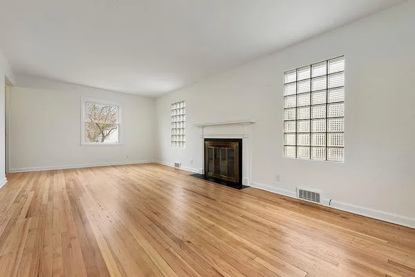 an empty room with windows and fireplace