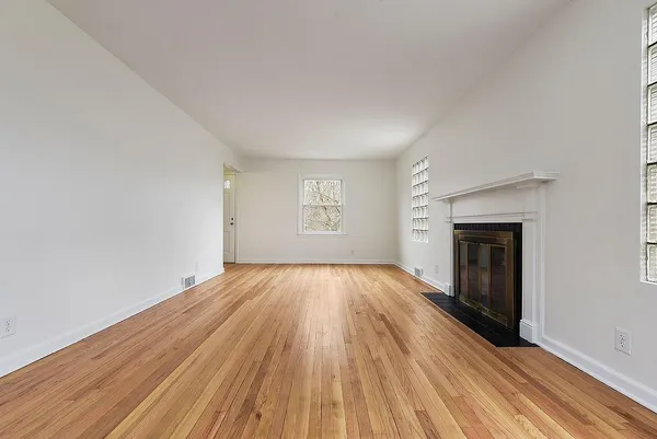 an empty room with wooden floor and a fireplace