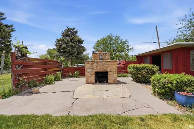 7576 South Jefferson Street Midvale, UT 84047 - Photo 37 of 53 Outdoor stone fireplace with a stone hearth, situated on a concrete patio