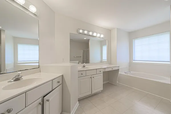 a bathroom with a sink double vanity granite tub shower and a mirror