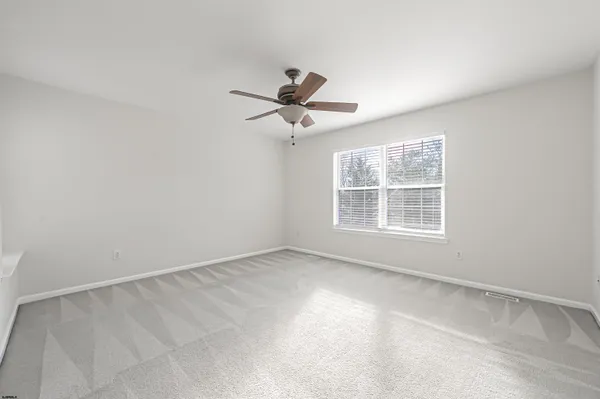 an empty room with a window and a ceiling fan
