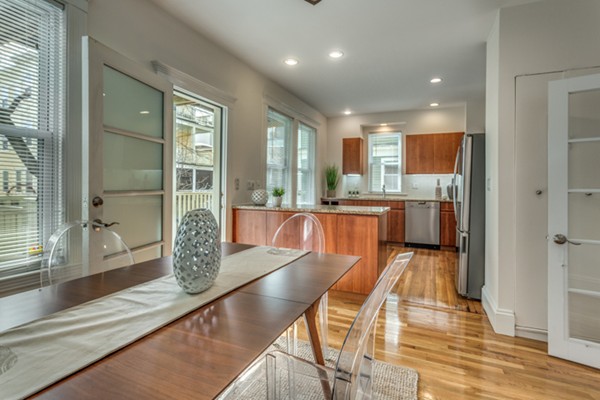 a dining hall with stainless steel appliances granite countertop a couch and a dining table with the view of bathroom