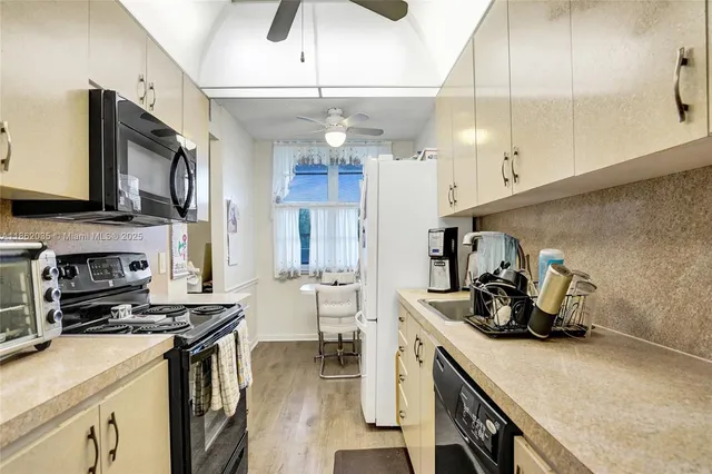 a kitchen with kitchen island granite countertop a sink appliances cabinets and a counter top space