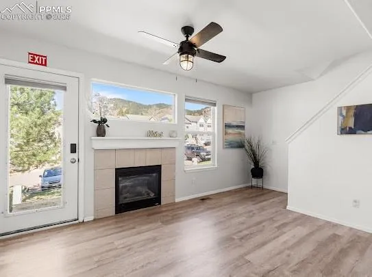 a view of an empty room with wooden floor fireplace and a window