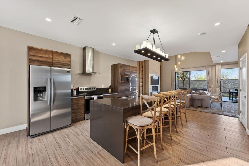 3119 Rockefeller Way Kissimmee, FL 34747 - Photo 4 of 57 a kitchen with stainless steel appliances a dining table chairs stove refrigerator and cabinets