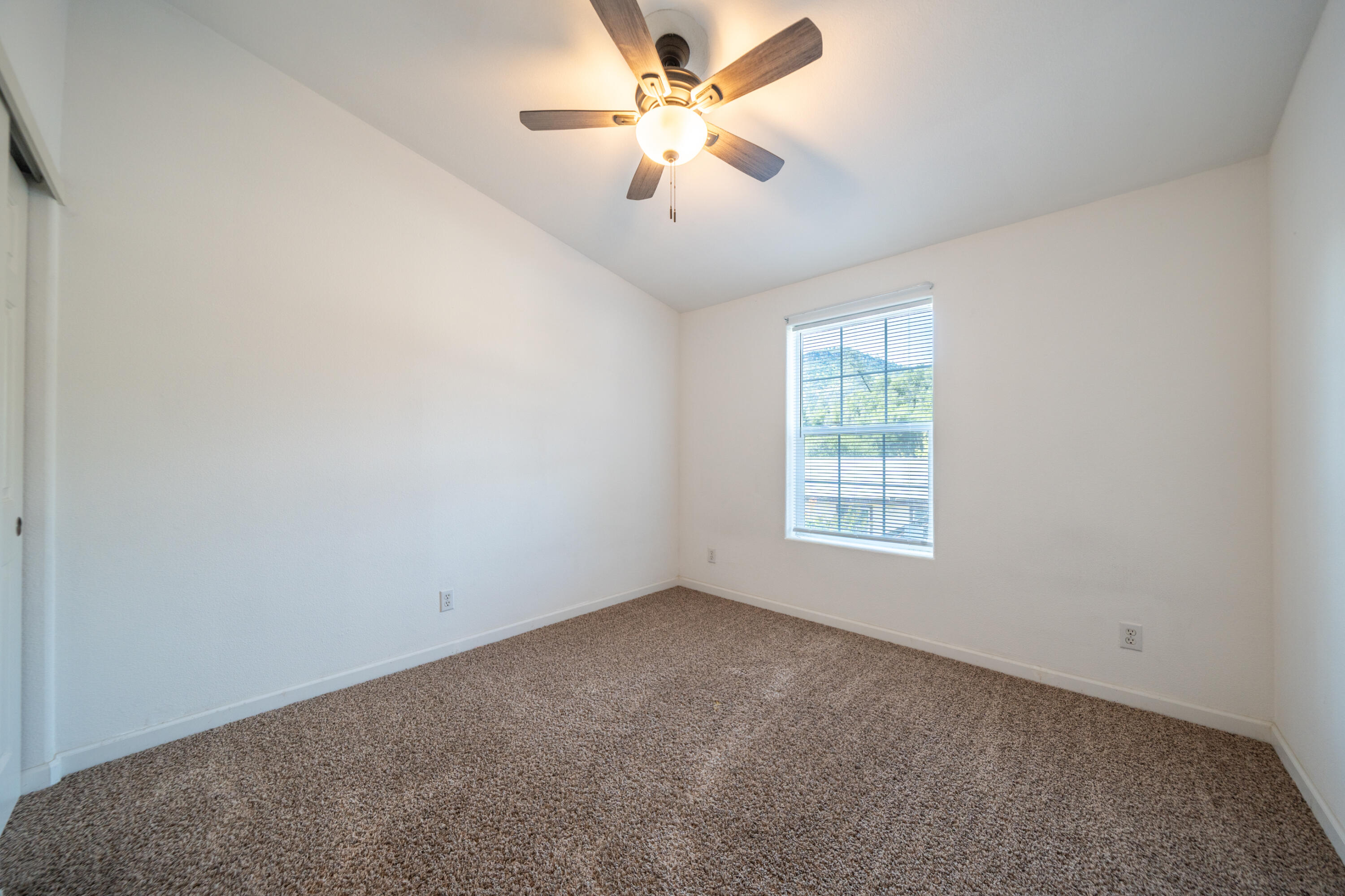 22151 Ravine Court Redding, CA 96003 - Photo 11 of 34 an empty room with a chandelier fan and windows