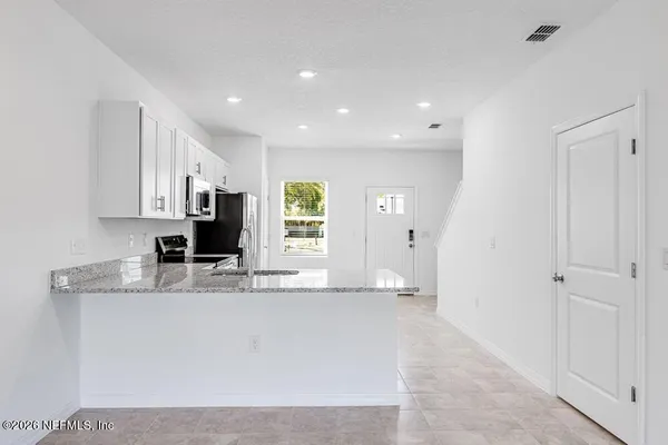 a large white kitchen with kitchen island a sink stainless steel appliances and cabinets