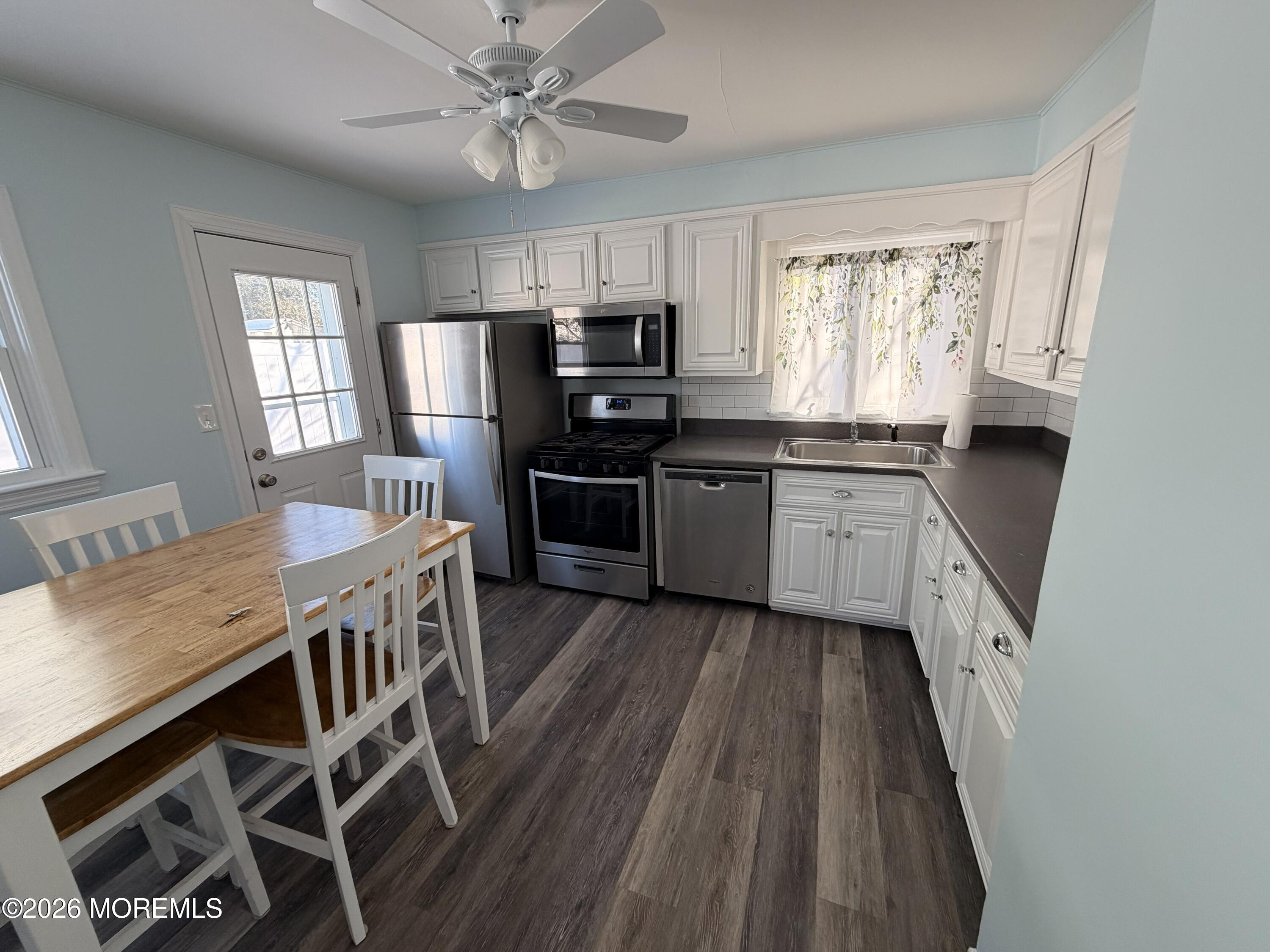 49 Ridge Place Neptune City, NJ 07753 - Photo 4 of 9 a kitchen with stainless steel appliances granite countertop a stove top oven a sink dishwasher a dining table and chairs with wooden floor