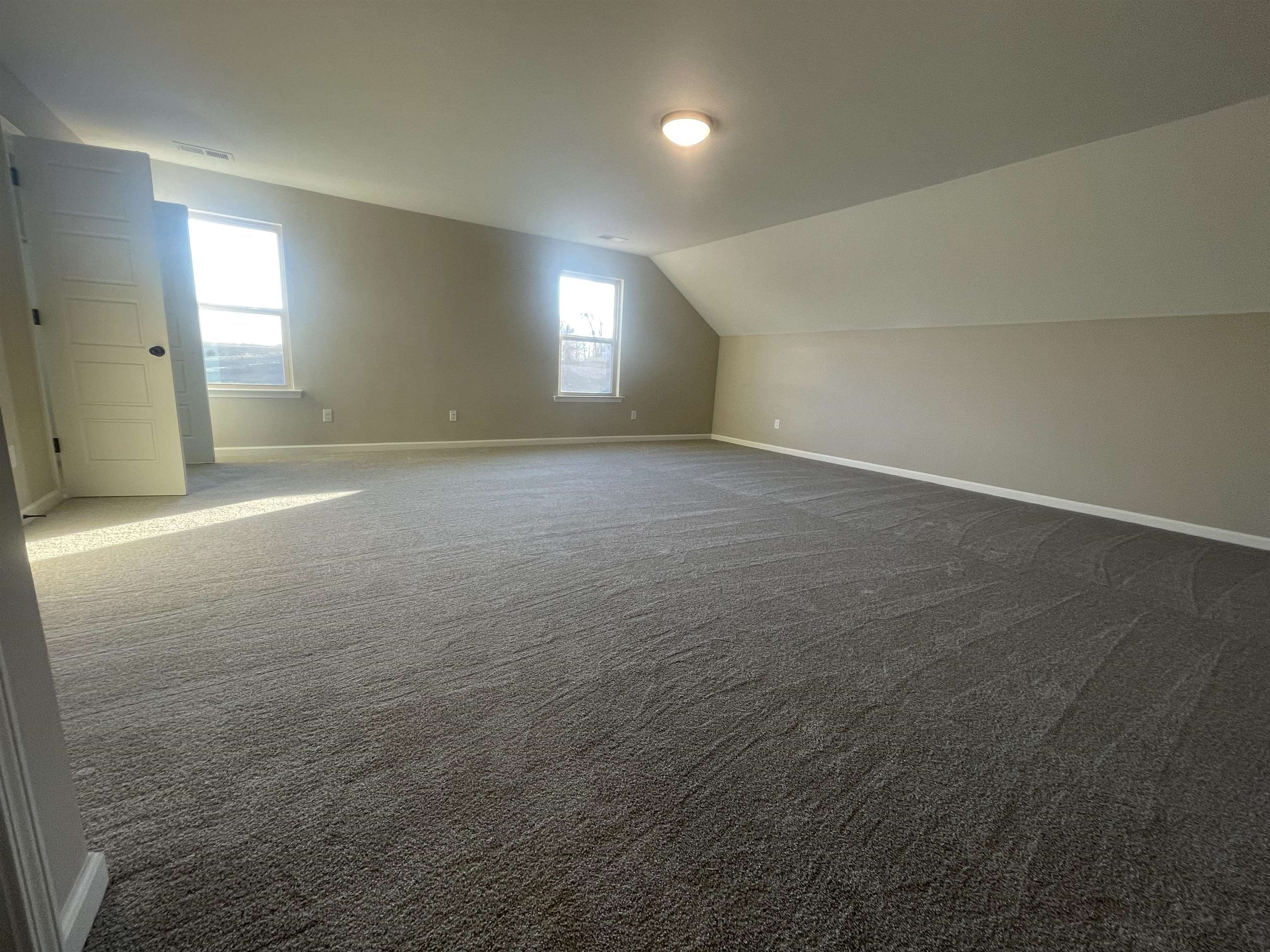 Bonus room featuring dark carpet and lofted ceiling
