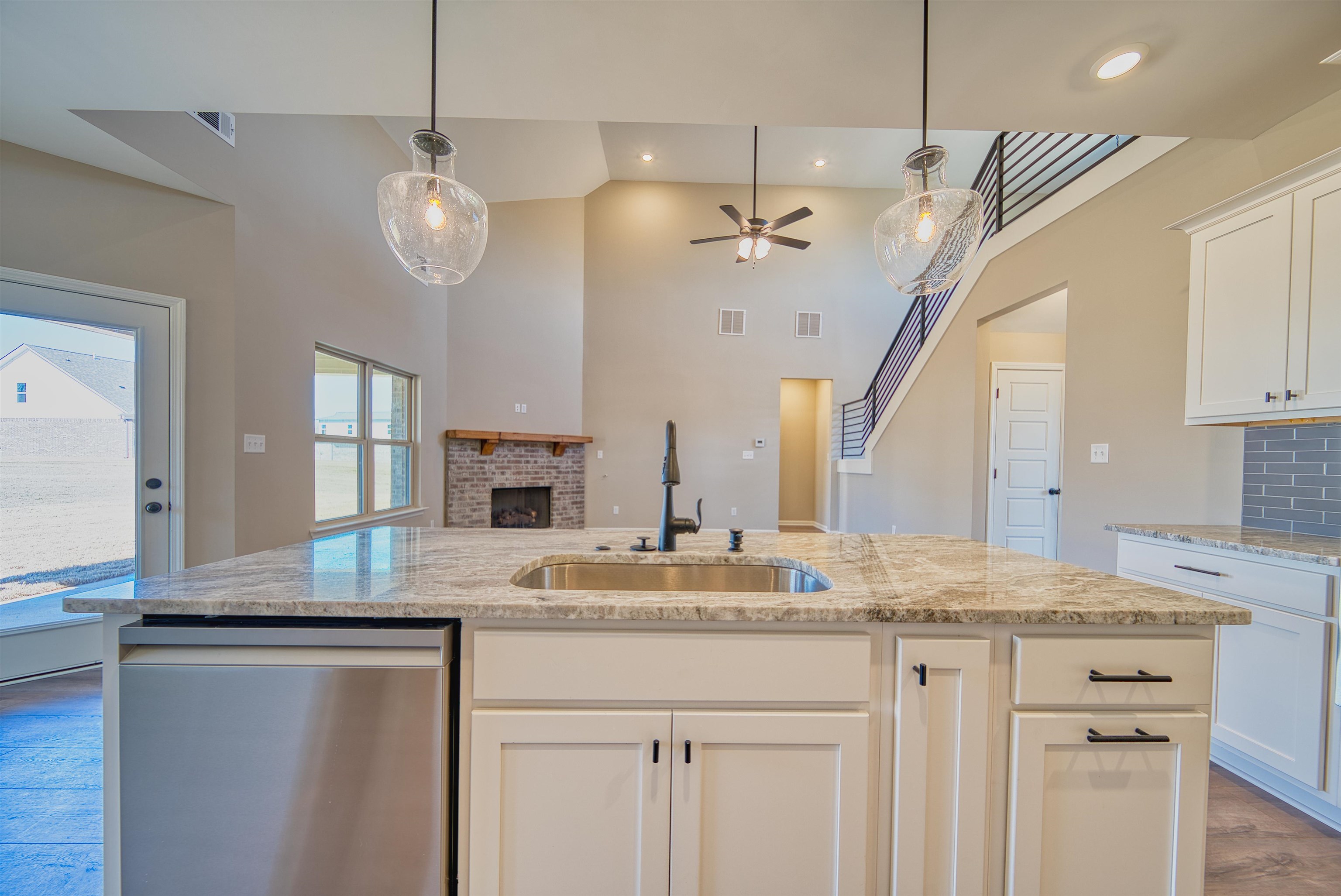 19 Columbia Way Atoka, TN 38004 - Photo 12 of 40 Kitchen with white cabinets, dark wood finished floors, stainless steel dishwasher, a brick fireplace, and a high ceiling