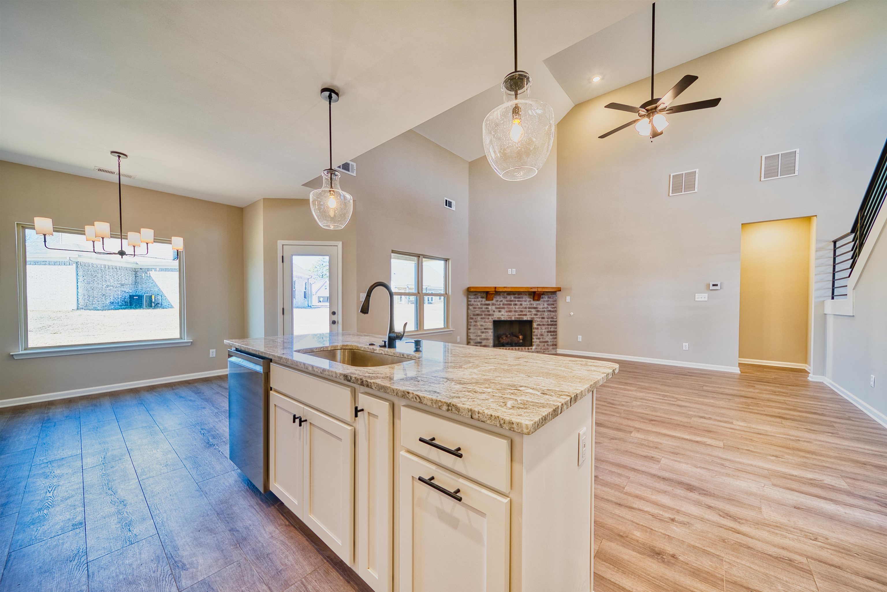 19 Columbia Way Atoka, TN 38004 - Photo 13 of 40 Kitchen featuring light wood-type flooring, a chandelier, light stone countertops, vaulted ceiling, and a fireplace