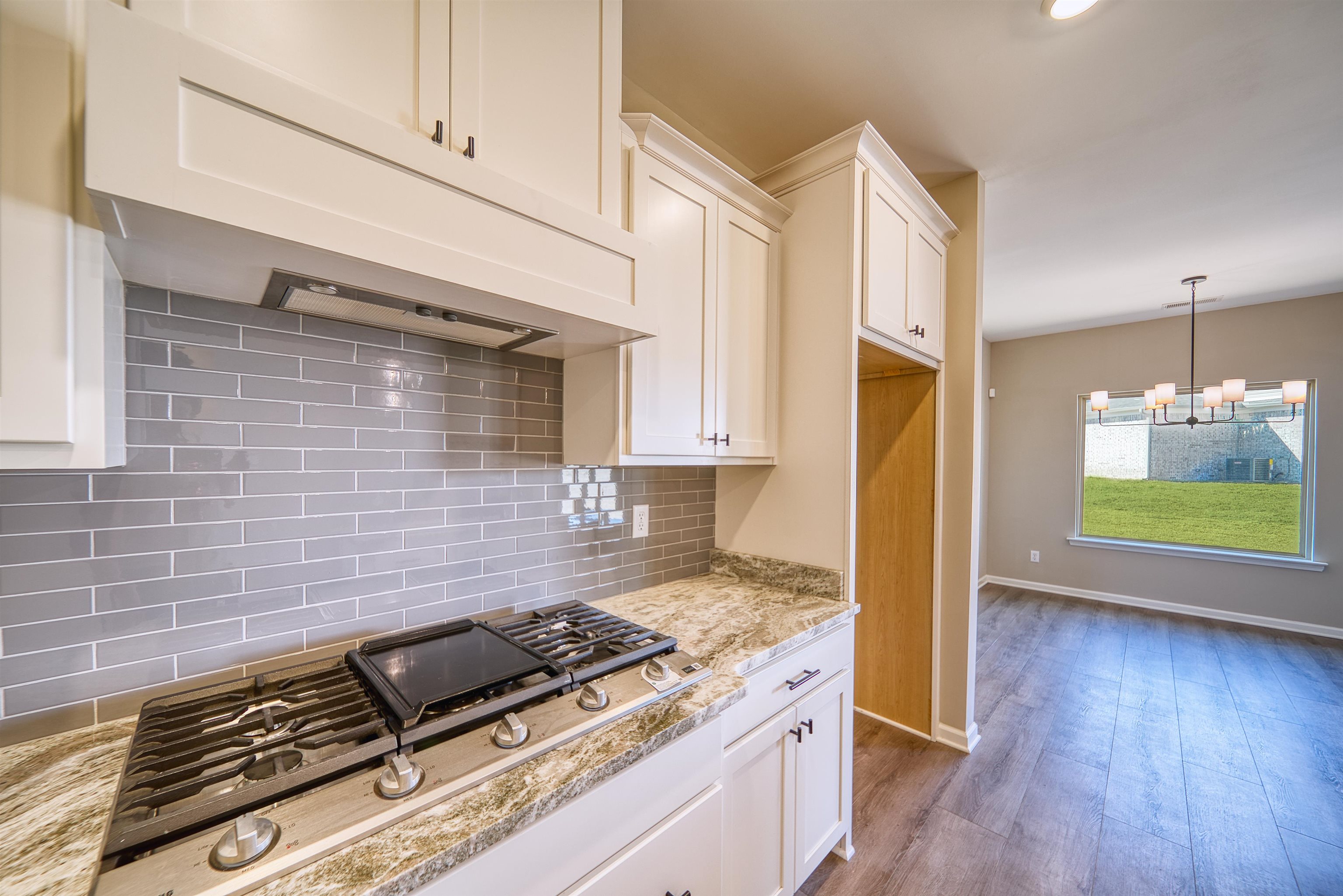19 Columbia Way Atoka, TN 38004 - Photo 14 of 40 Kitchen with stainless steel gas stovetop, light wood-style floors, white cabinets, light stone counters, and a chandelier