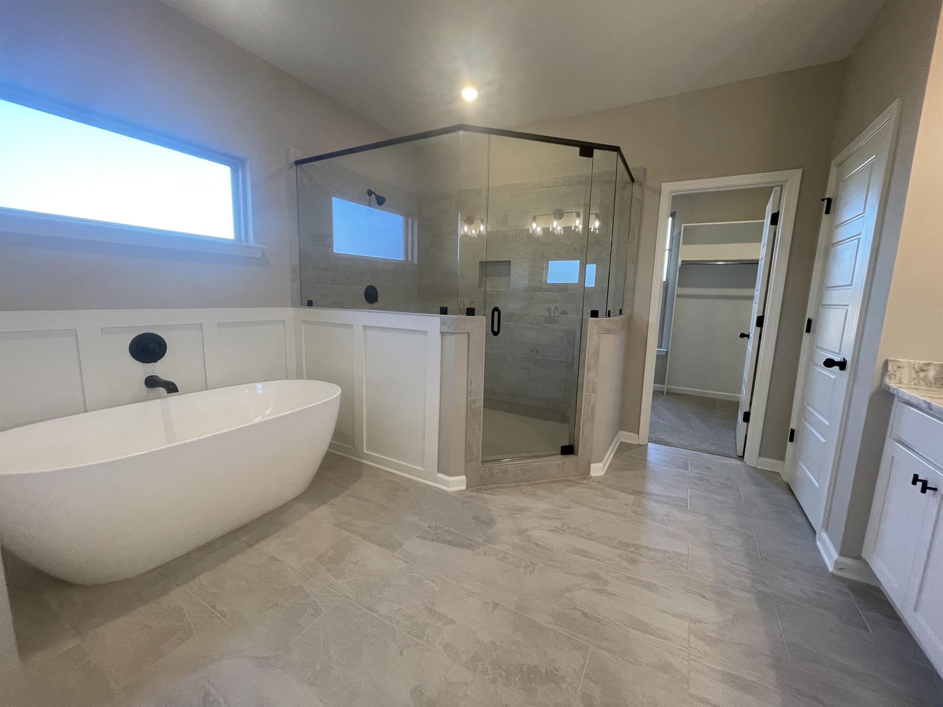 19 Columbia Way Atoka, TN 38004 - Photo 14 of 28 Bathroom with vanity, a walk in closet, a stall shower, a soaking tub, and wainscoting