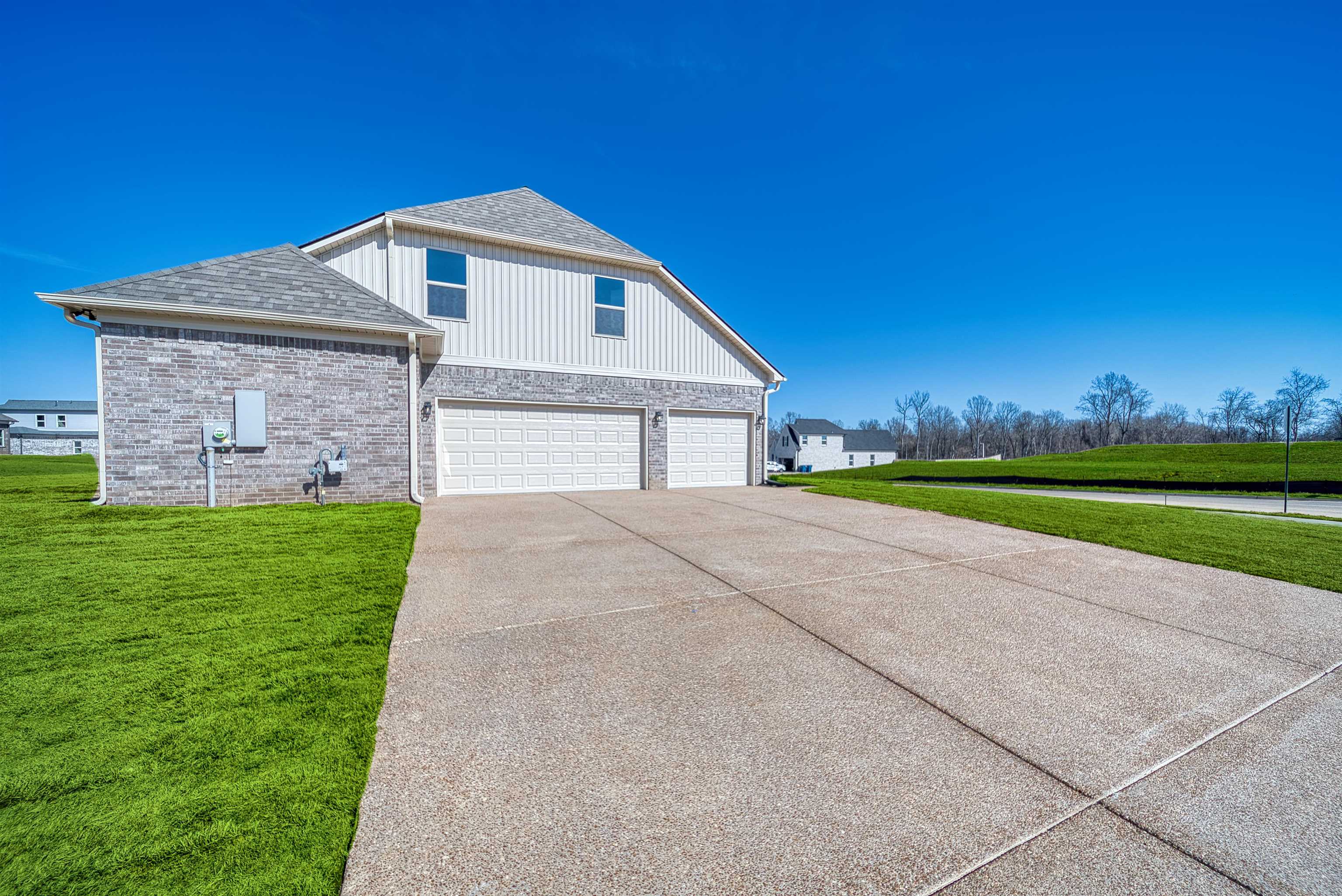19 Columbia Way Atoka, TN 38004 - Photo 2 of 40 View of home's exterior featuring a yard, a garage, driveway, brick siding, and a shingled roof
