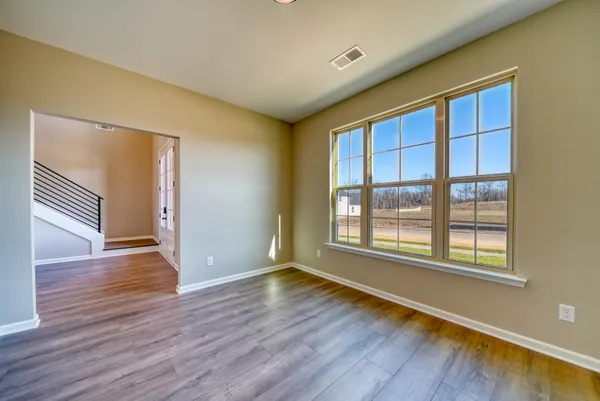 a view of an empty room with wooden floor and window