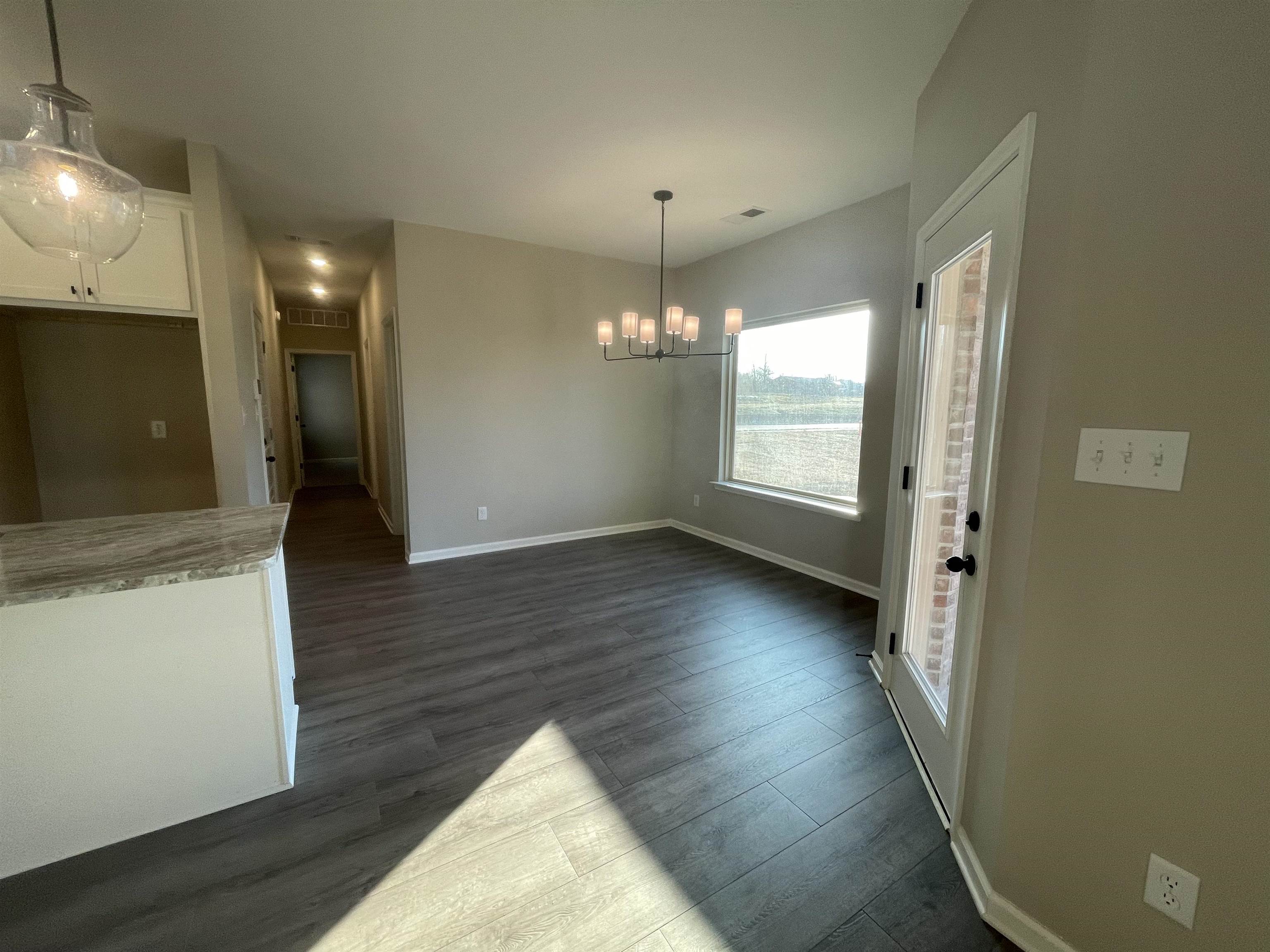 19 Columbia Way Atoka, TN 38004 - Photo 3 of 28 Unfurnished dining area featuring dark wood finished floors and hanging lights