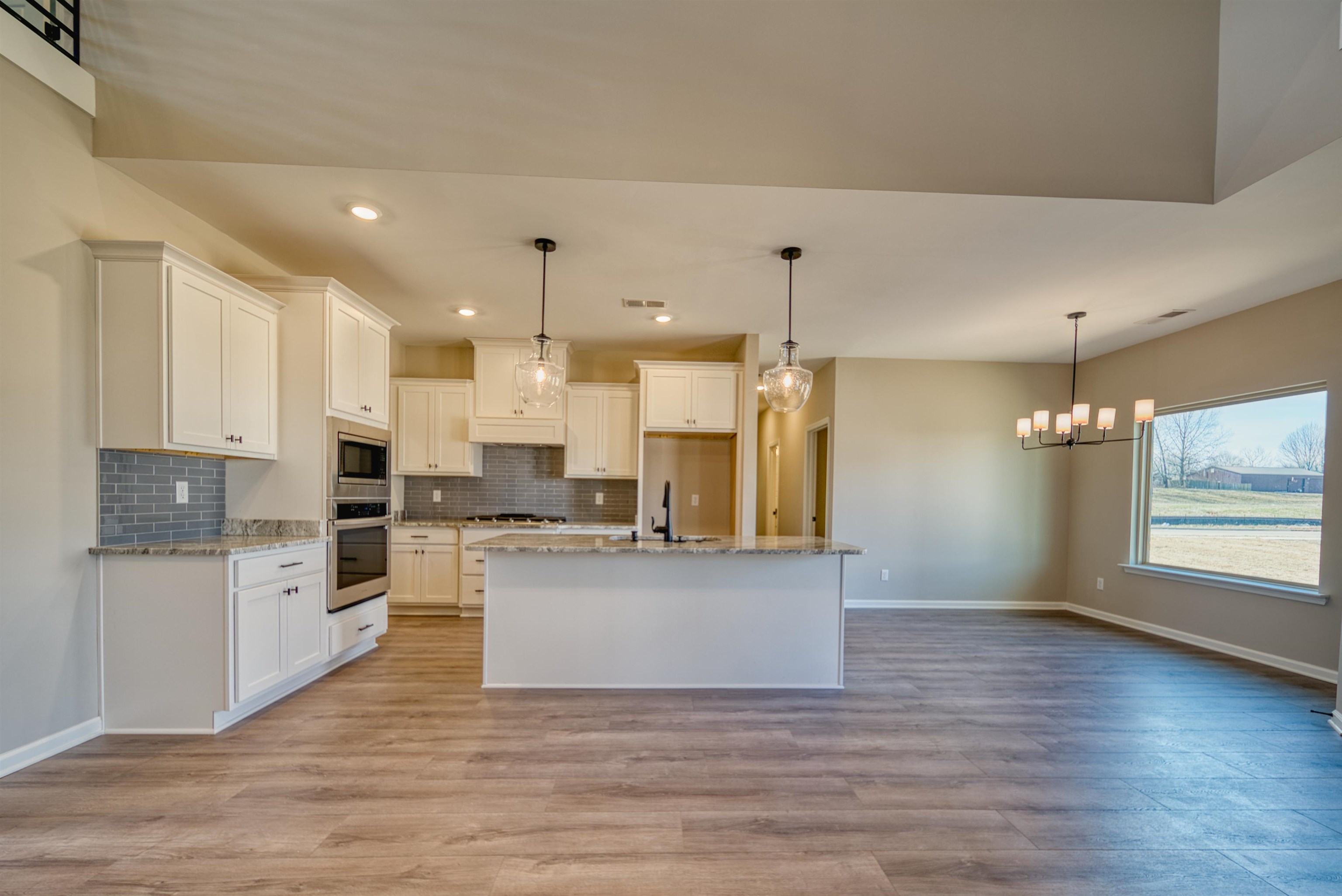 19 Columbia Way Atoka, TN 38004 - Photo 8 of 40 Kitchen featuring hanging lights, a kitchen island with sink, white cabinetry, and light wood-style floors